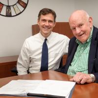 Two men sitting at table smiling.